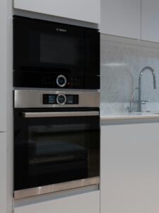 Contemporary comfortable white interior of kitchen with microwave oven and embedded electric stove